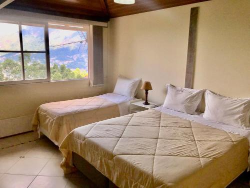 a bedroom with two beds and a window at Pousada In Garden in Teresópolis