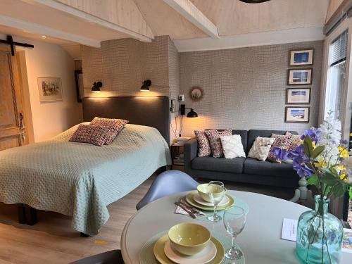 een slaapkamer met een bed, een bank en een tafel bij Studio Clematis Bergen in Bergen