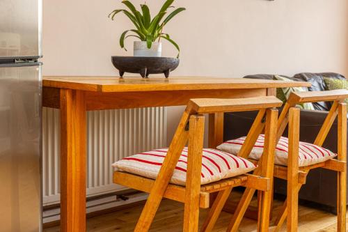 a wooden table with two chairs and a plant on it at 2BR wbalcony, Battersea, 5min Clapham Junction St in London