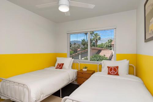 Duas camas num quarto com paredes amarelas e brancas em \\Golf and Couples Oasis// Midcentury w/6 Pools Hot Tub em Palm Springs