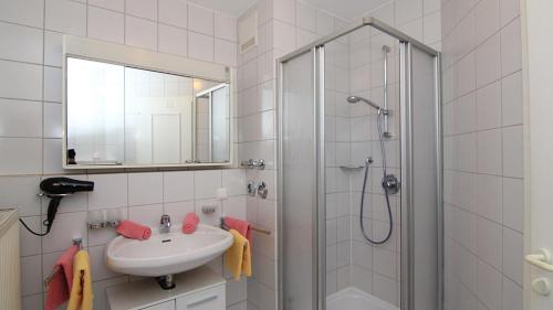 y baño blanco con lavabo y ducha. en Ferienwohnungen Marianne Hölzl, en Schönau am Königssee