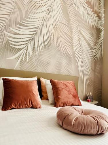 ein Bett mit zwei Kissen und ein Gemälde von Palmblättern in der Unterkunft Charmant petit appartement. in Lüttich