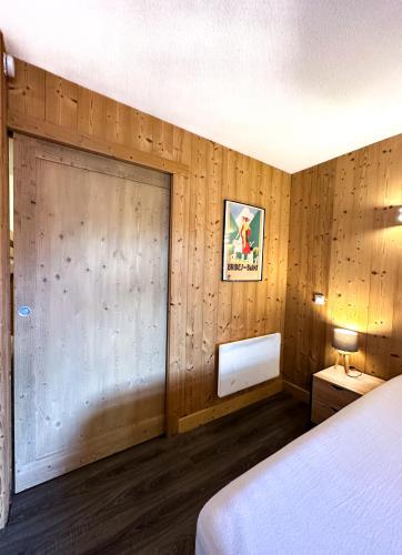 - une chambre avec un mur en bois et une porte dans l'établissement 2- Studio Brides-les-bains tout confort avec vue Vanoise, à Brides-les-Bains