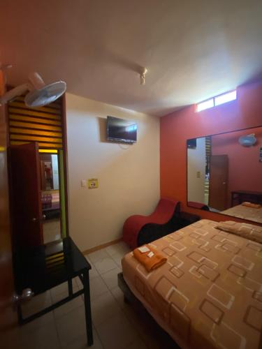a bedroom with a bed and a chair and a mirror at PUNTO G in Tumbes