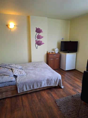 a bedroom with a bed and a flat screen tv at Pensjonat Koral in Darłówko