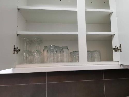 a shelf with many glass jars on it at Newly Renovated Cosy 1 bed flat, 4 minutes walk to Town Centre, 3 minutes walk to the train station, Free parking, Modern, fresh and spacious living room, Netflix ready smart TV, Wifi in Wellingborough