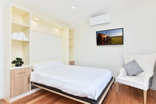 a small bedroom with a bed and a chair at Odyssean Farmstay Cabin in Cessnock