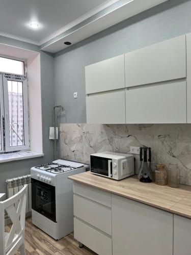 eine Küche mit weißen Schränken und einer Mikrowelle auf der Theke in der Unterkunft квартира in Aqtau