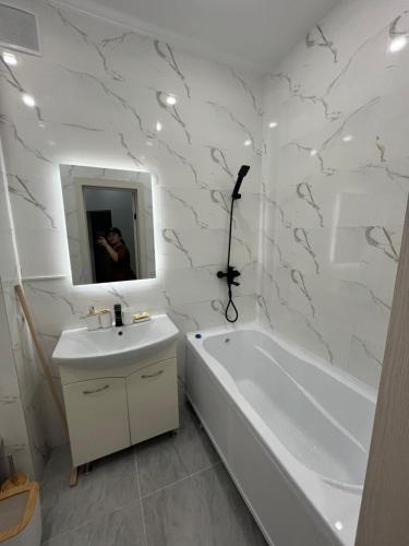 ein Badezimmer mit einer Badewanne, einem Waschbecken und einer Badewanne in der Unterkunft квартира in Aqtau