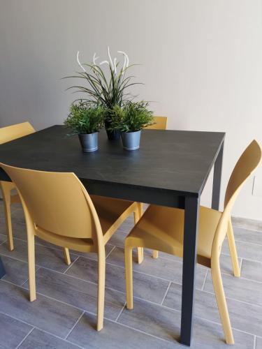 a black dining table with yellow chairs and plants on it at Il Piacere in Pineto