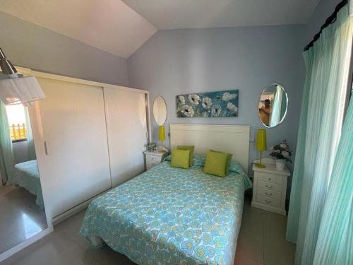 a bedroom with a bed with green pillows and a mirror at Santa Fe Bunglow Deluxe Playa Del Ingles in Maspalomas