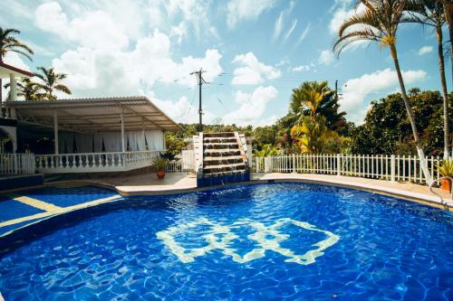 a large blue swimming pool with a white fence and palm trees at FINCA VILLA ESMERALDA in Pereira