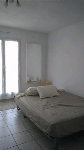 un lit dans une chambre blanche avec une fenêtre dans l'établissement Logement entier - Les Baumettes, à Nice