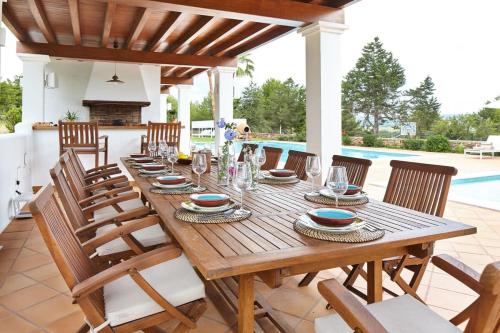een houten tafel met stoelen en een eetkamer bij Private Family Size Villa in Nature with Tennis, Basketball and Football Courts for Holidays and Retreats in Sant Rafael de Sa Creu