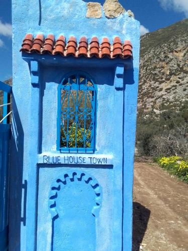 a blue house with a window on a dirt road at Blue House Town in Chefchaouene