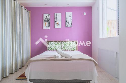 a bedroom with a purple wall and a bed at Apartamento a 300m da Praia do Forte em Cabo Frio in Cabo Frio