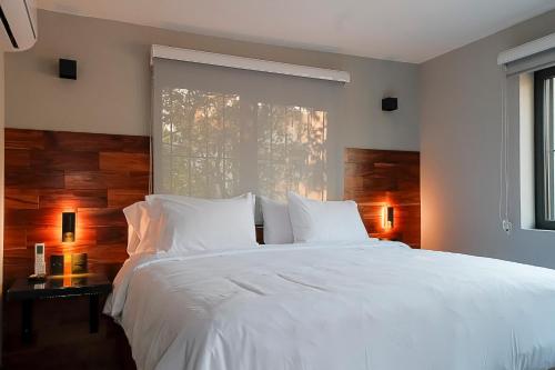 1 dormitorio con 1 cama blanca grande y ventana en Casa Serenos, en Ciudad de México