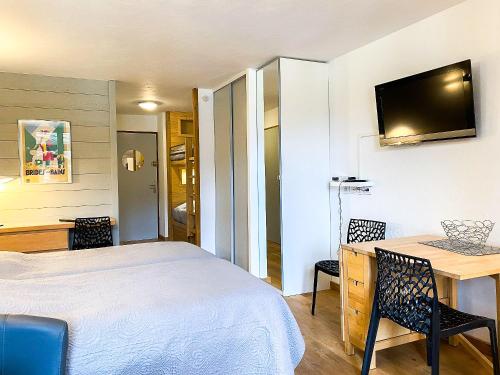 Schlafzimmer mit einem Bett, einem Schreibtisch und einem TV in der Unterkunft 3- Charmant studio Brides-les-Bains in Brides-les-Bains