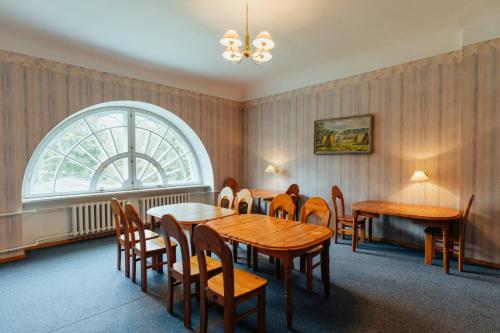 a dining room with tables and chairs and a window at Naukšēnu muiža in Naukšēni