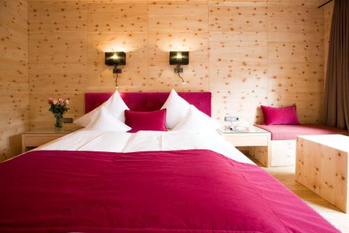 a bedroom with a large red bed with pink pillows at Minglers Sportalm - Das Gourmet- und Genießerhotel in Kirchberg in Tirol