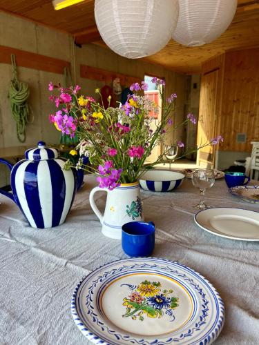 a table with a plate and a vase with flowers at Waterfront Rorbu - By the Beach in Bud