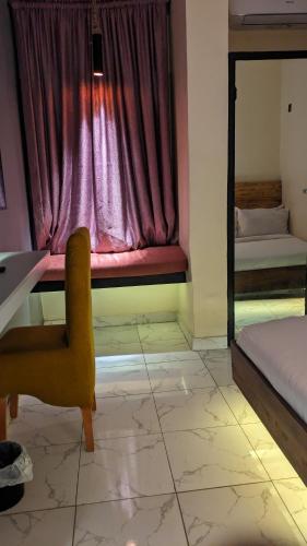Zimmer mit einem Bett, einem Stuhl und einem Fenster in der Unterkunft Red Skillet in Lagos