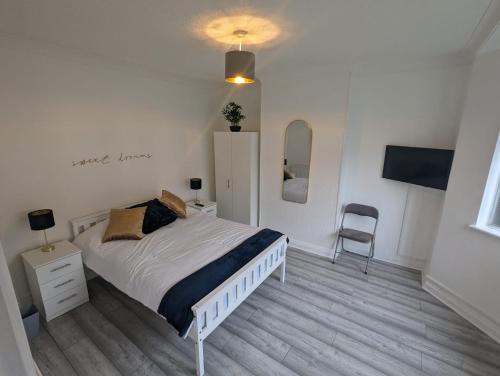 a white bedroom with a bed and a chair at The Manor Guest House in Wembley in London