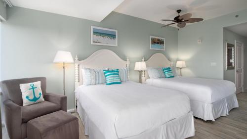 a bedroom with two beds and a chair and a ceiling fan at Luau II 7226 Studio in Destin