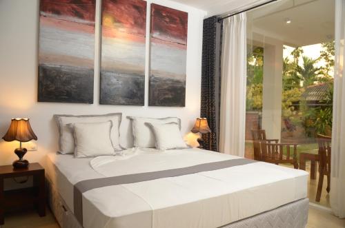a bedroom with a large white bed with paintings on the wall at The Residence Bentota in Bentota