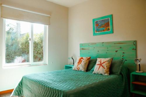 - une chambre avec un lit doté d'une couette verte et d'une fenêtre dans l'établissement Agua de Mar I, à Mar de Cobo