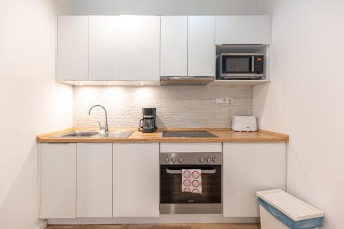Una cocina con gabinetes blancos, un fregadero y una estufa. en Gems of Budapest - Ruby Unit, en Budapest