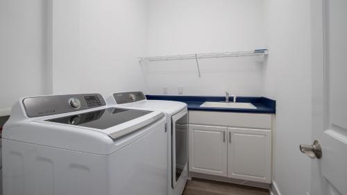 a white laundry room with a washer and a sink at Slice of Paradise in Destin