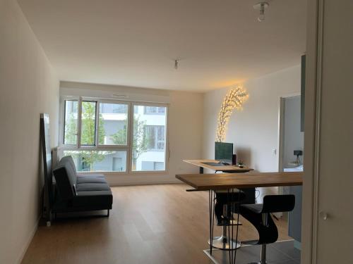 ein Wohnzimmer mit einem Tisch und einem Stuhl in der Unterkunft Charmant appartement à 20 min de Paris centre in Bagneux