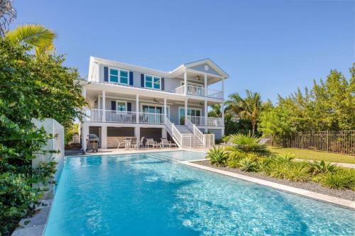 a house with a swimming pool in front of a house at Spindrift House -Huge Pool, Dock in Stock Island