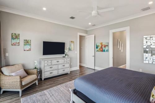 a bedroom with a bed and a tv and a chair at Spindrift House -Huge Pool, Dock in Stock Island