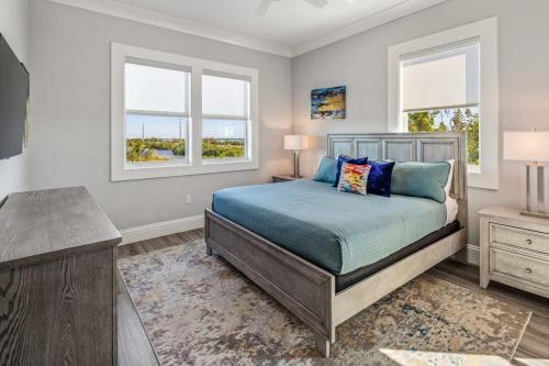 a bedroom with a bed and two windows at Spindrift House -Huge Pool, Dock in Stock Island