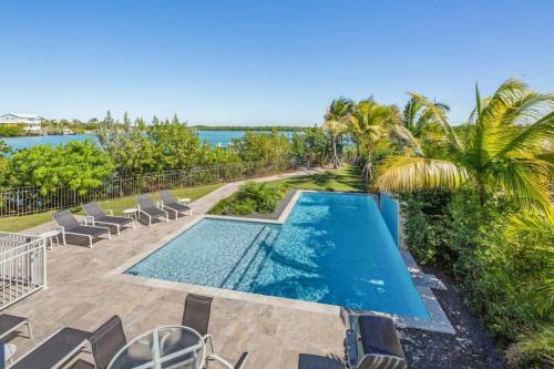 a swimming pool with chairs and the ocean in the background at Spindrift House -Huge Pool, Dock in Stock Island