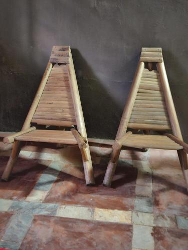 dwie drewniane drabiny siedzące obok ściany w obiekcie YAA HOMÉ w mieście Kpalimé
