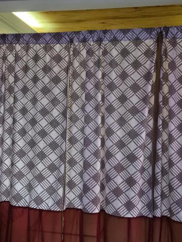 una cortina de color púrpura y blanco a cuadros en una habitación en YAA HOMÉ, en Palimé