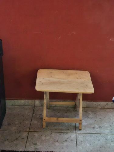 drewniana ławka siedząca przed czerwoną ścianą w obiekcie YAA HOMÉ w mieście Kpalimé