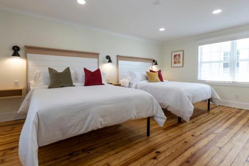 a bedroom with two beds with white sheets and red pillows at Cape Henry House Inn at Old Beach in Virginia Beach