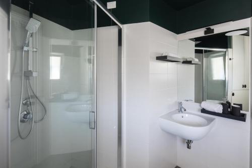 La salle de bains blanche est pourvue d'un lavabo et d'une douche. dans l'établissement Loft 36 by Omen Hospitality, à Rome