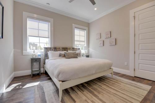 a white bedroom with a bed and two windows at Mirador House -Pool & Dock! in Stock Island