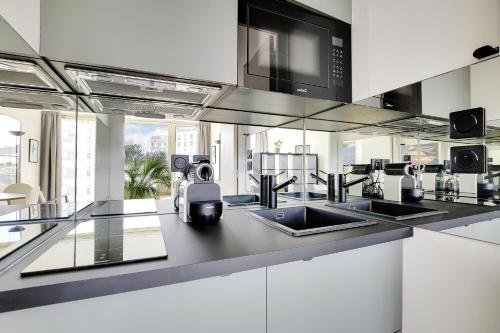 une cuisine avec un évier et un micro-ondes dans l'établissement VICTOR HUGO - ARC de TRIOMPHE - TROCADERO, à Paris