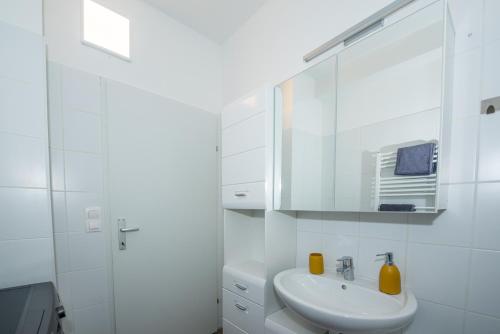 ein weißes Badezimmer mit einem Waschbecken und einem Spiegel in der Unterkunft Lipi Apartment in Wien