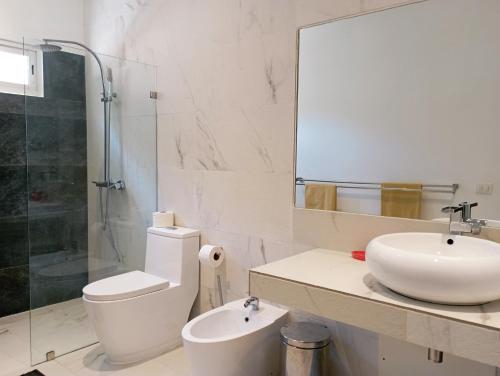 ein Badezimmer mit einem Waschbecken, einem WC und einem Spiegel in der Unterkunft Appartement 1 CH centre Las Terrenas 100 m2 piscine et parking in Las Terrenas
