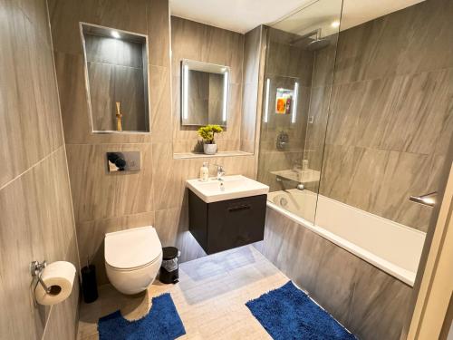 a bathroom with a toilet and a sink and a tub at Bright & Spacious-Secured flat near slough station in Slough