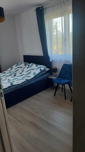ein Schlafzimmer mit einem Bett, einem Stuhl und einem Fenster in der Unterkunft Widokowy Zakątek in Czorsztyn