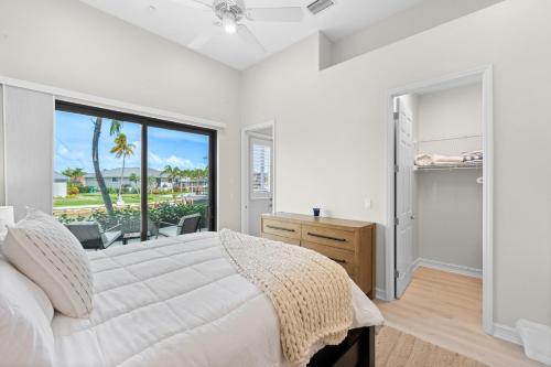 a white bedroom with a large bed and a window at Sweet Waterfront Retreat in Marco Island