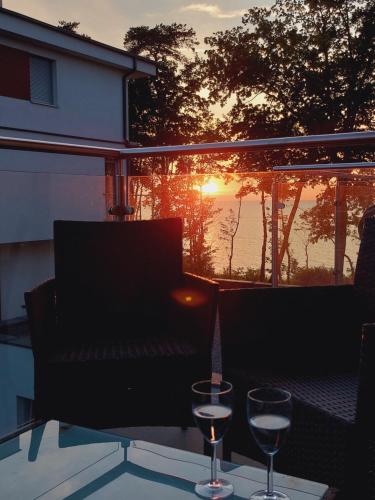 dwa kieliszki wina siedzące na stole z zachodem słońca w obiekcie Sea view balcony & pool access w Rewalu